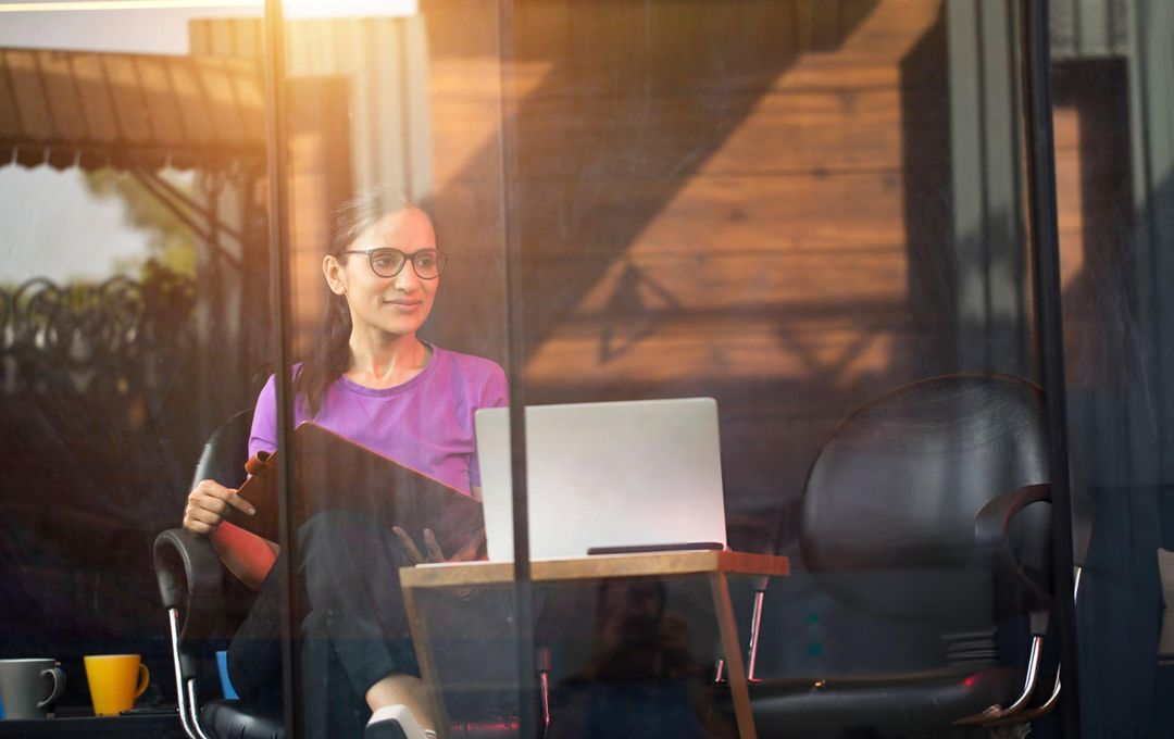 A woman working at a laptop in a sunlit office